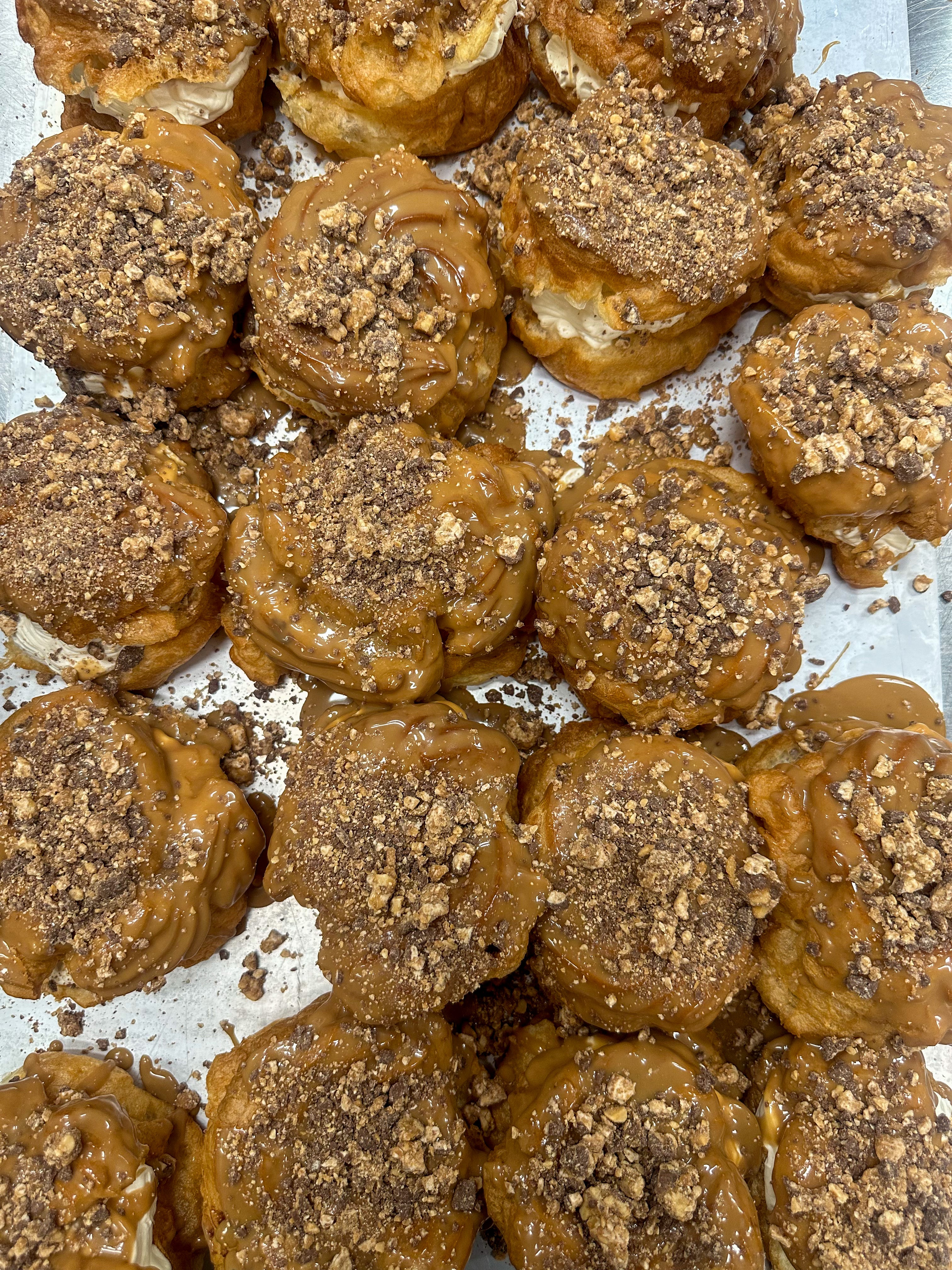 Nokkrar bollur saman, mynd tekin ofan frá og sést í karamellu krem ofan á vatsndeigsbollum með snickerskurli